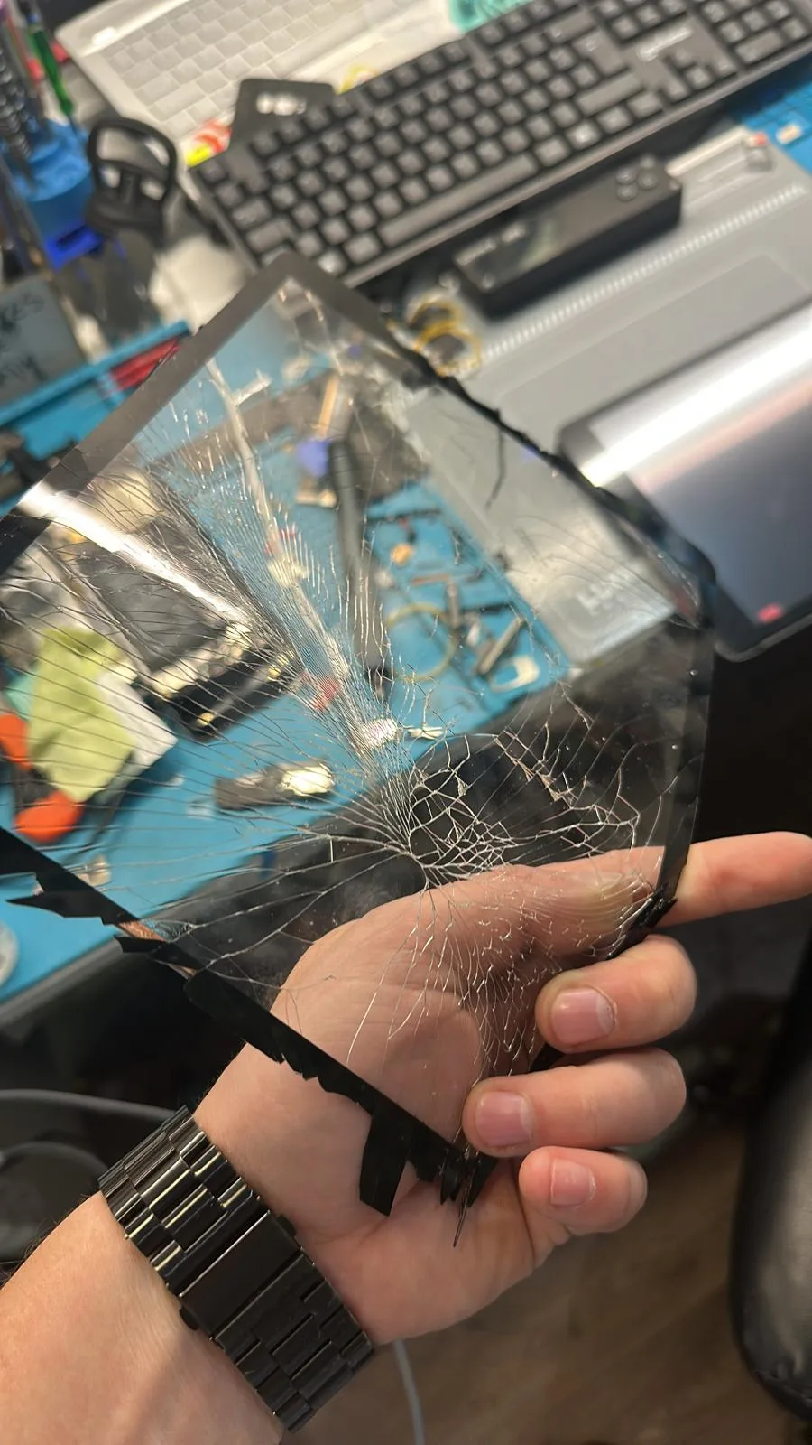 Bucăți din sticla spartă a unui ecran, scoase cu grijă de pe display